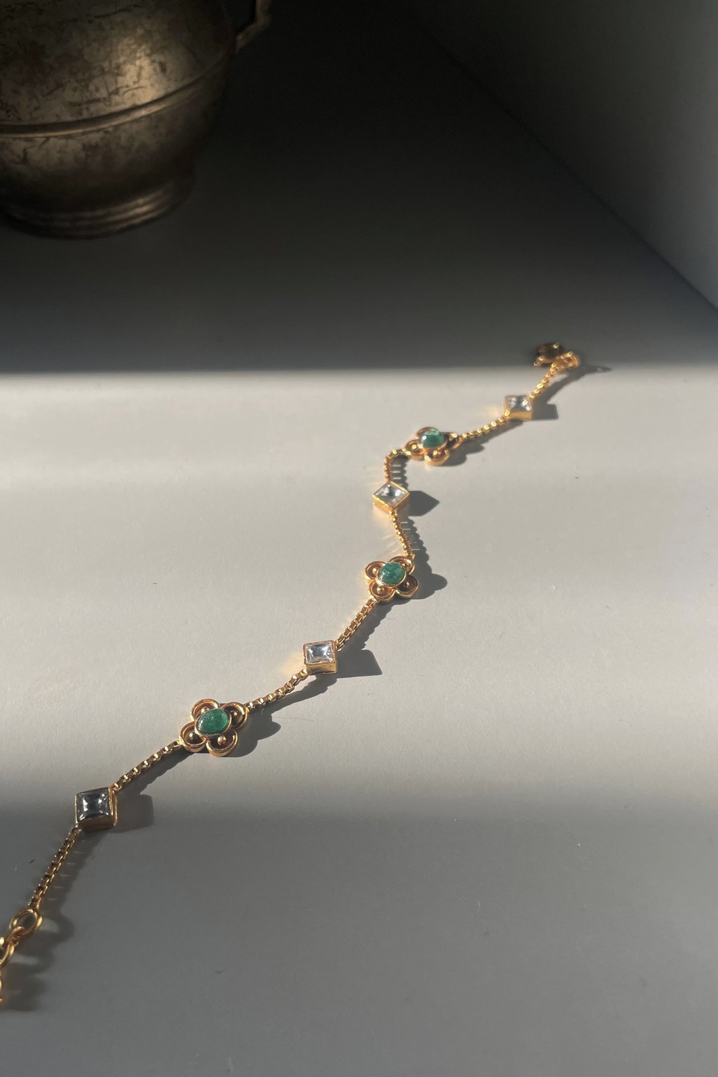 Jhilmil Bracelet crafted in 925 silver with 22k gold plating, featuring a slender chain adorned with green aventurine and white Jadau stones.