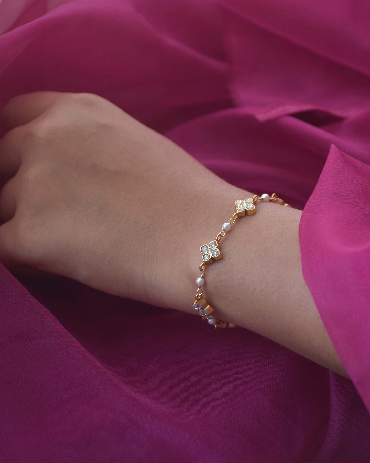 Kasturi Bracelet crafted in 925 silver with 18k gold plating, featuring intricate 4-petal floral motifs and accented with lustrous freshwater pearls.