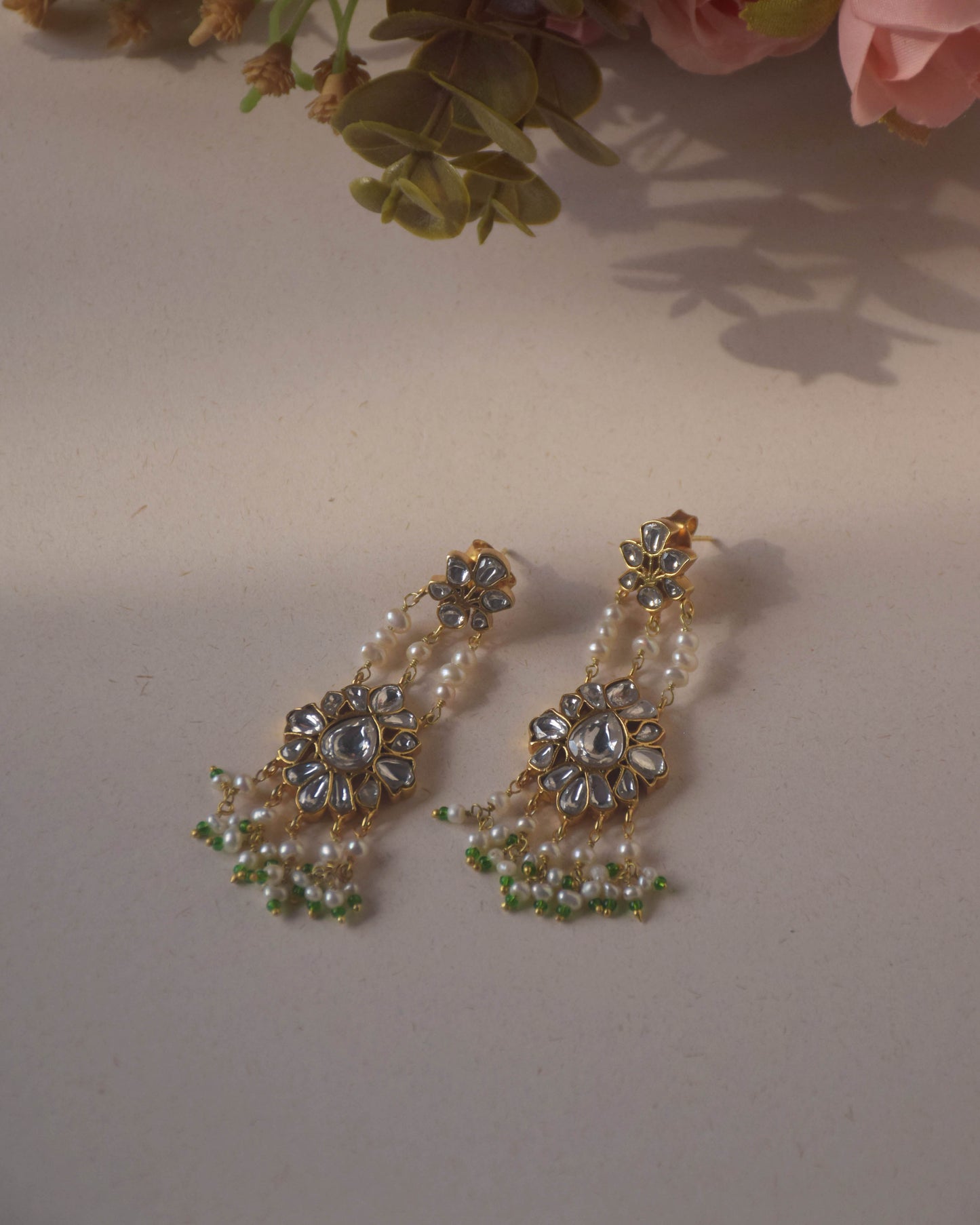 Jadau Pearl Drop Earrings crafted in 925 sterling silver featuring a flower-shaped top studded with jadau stones and an intricate jadau stone-studded motif suspended from three strands of pearls.