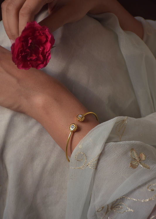 Bindiya Bangle crafted in 925 silver with 22k gold plating, featuring an adjustable design adorned with a single white Jadau stone and intricate gold wirework.