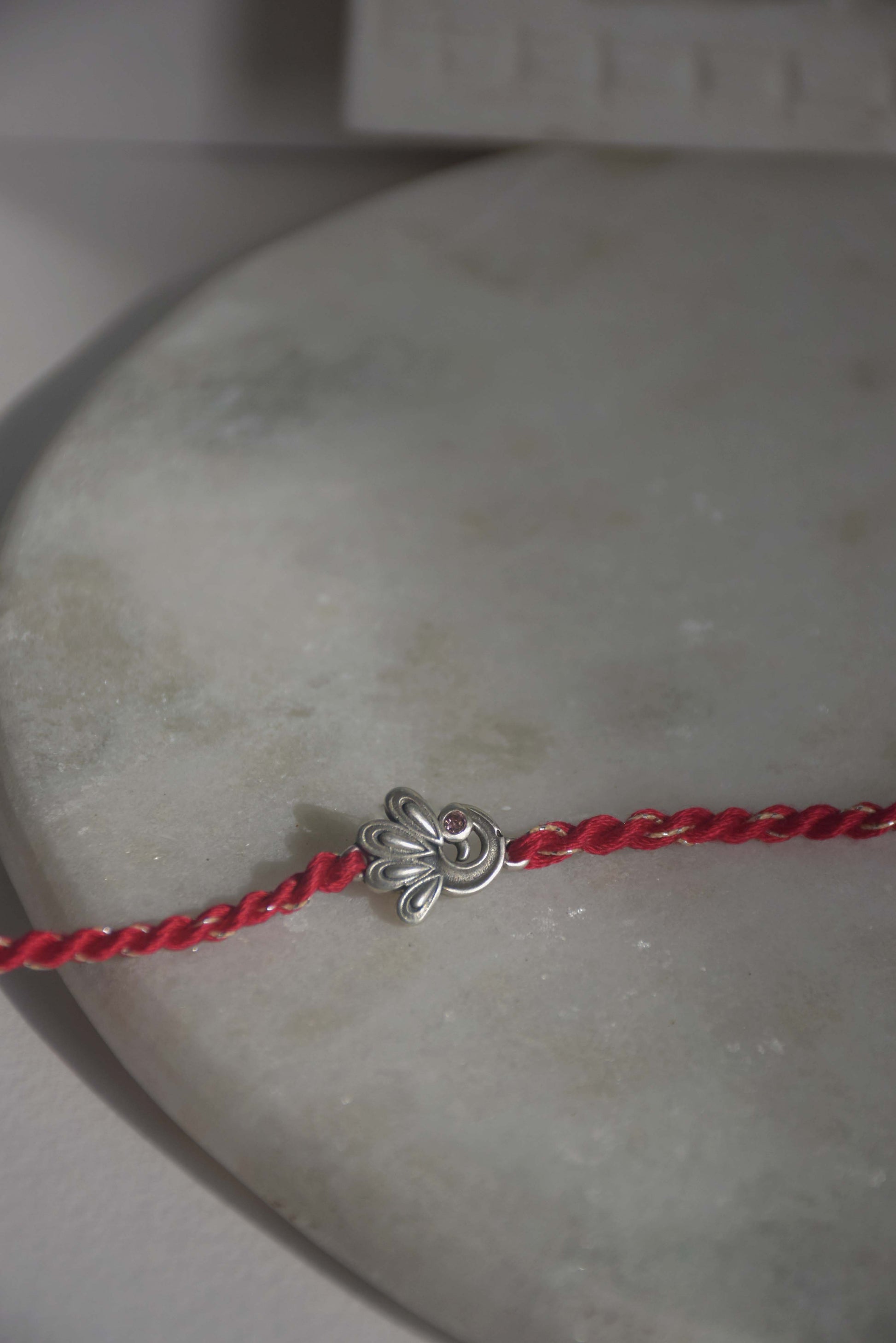 92.5 sterling silver Rakhi adorned with real freshwater pearls and cotton thread.