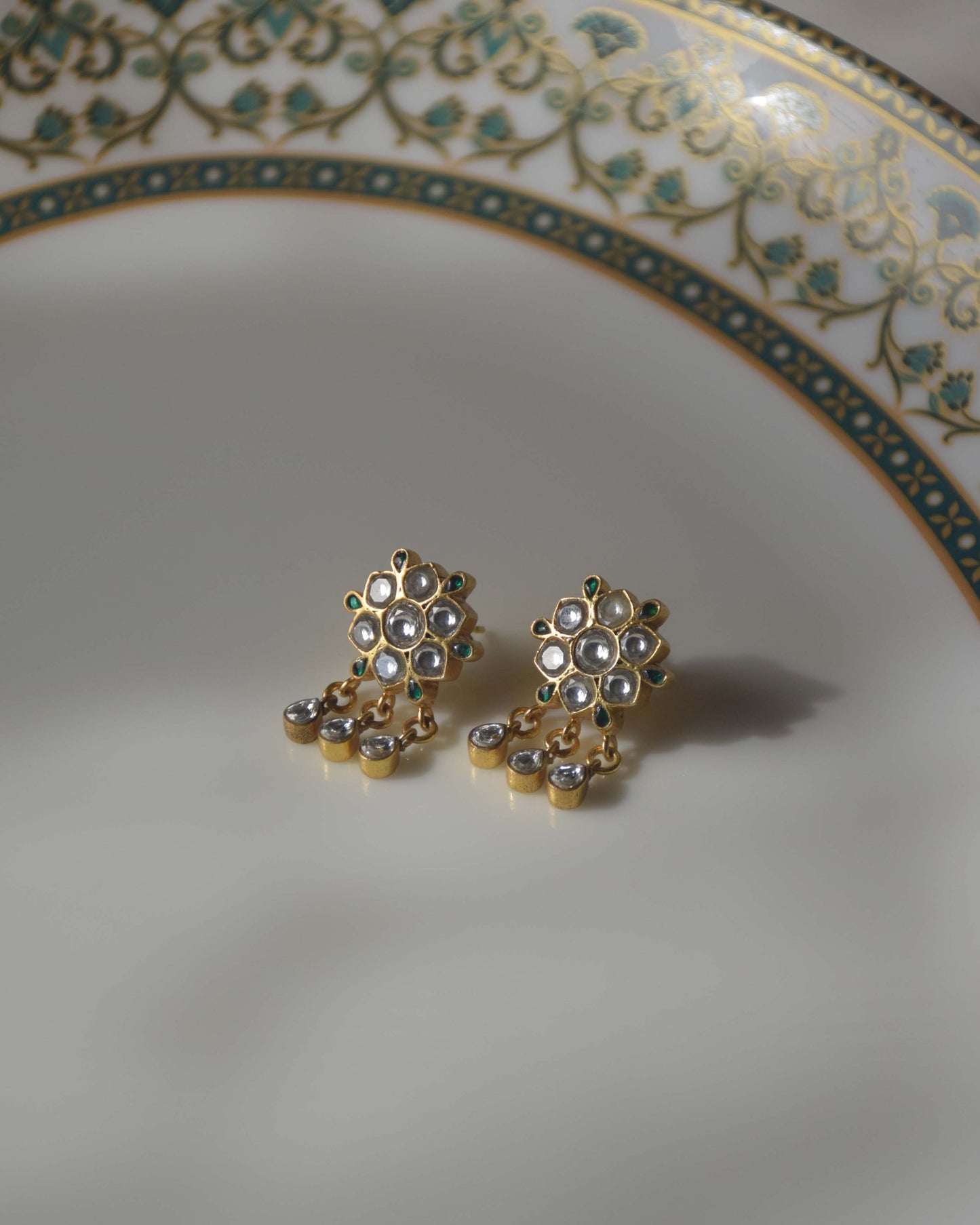 crafted in 925 silver, showcase an enchanting flower motif adorned with Jadau Stones and delicate hanging drops.
