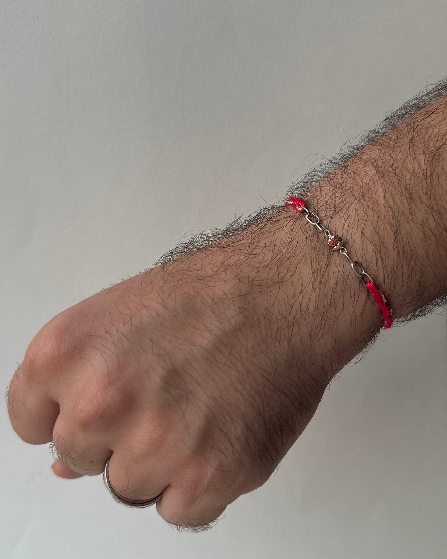 Hand with a red bracelet on a plain background