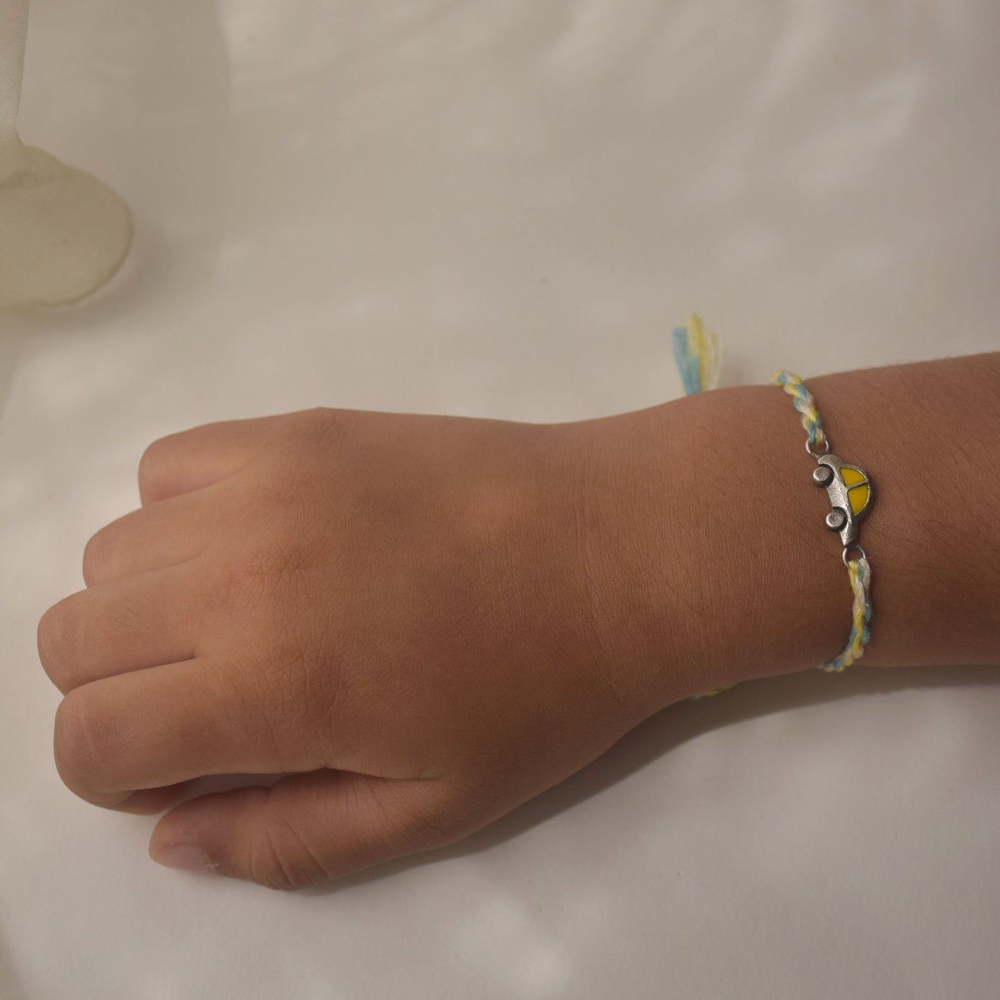Hand wearing a colorful Rakhi in 925 silver with a on a plain background
