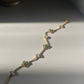 Jhilmil Bracelet crafted in 925 silver with 22k gold plating, featuring a slender chain adorned with green aventurine and white Jadau stones.