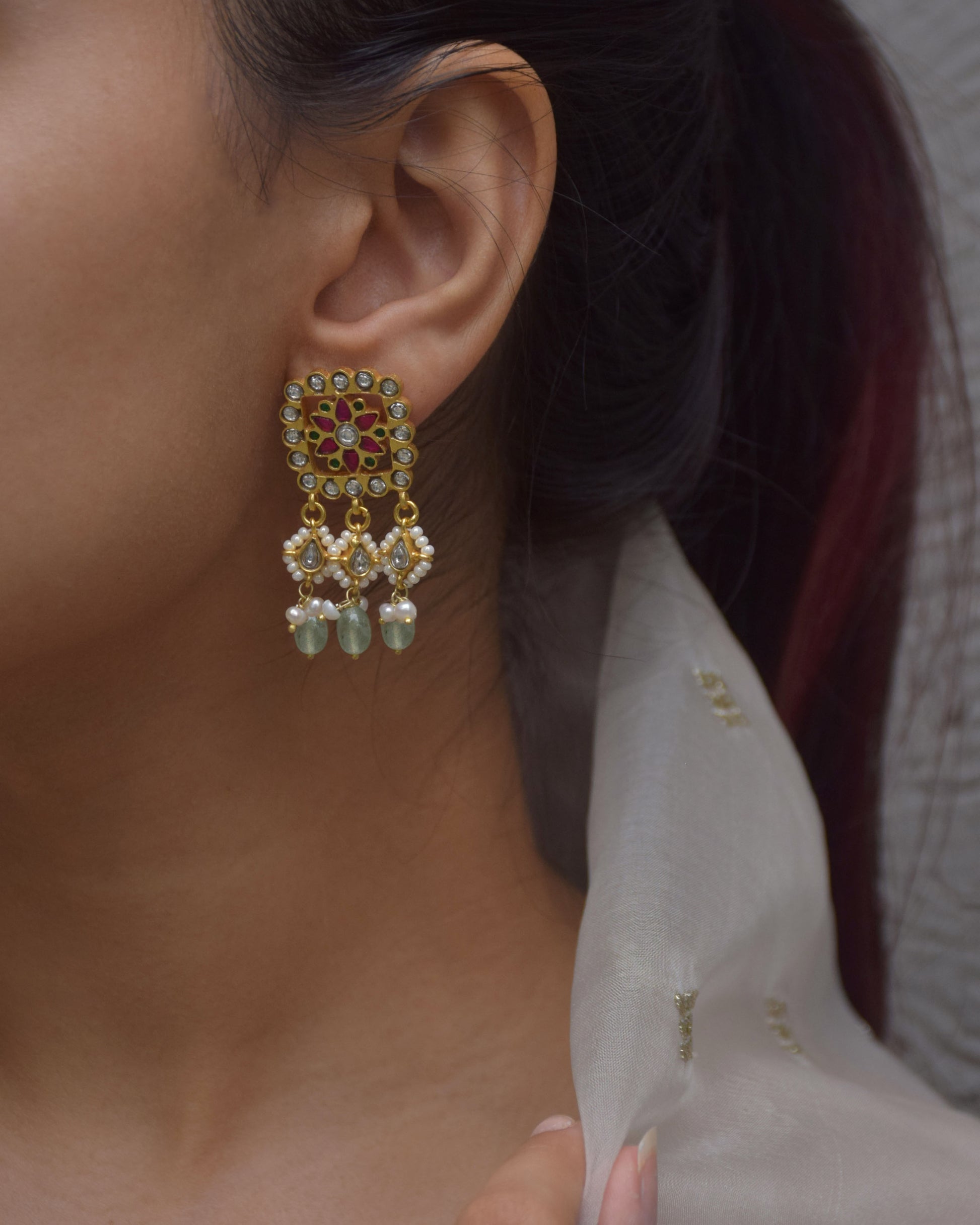 crafted Aayat Earrings in 925 silver. These square-shaped treasures boast an intricate floral centerpiece, encircled by petal-shaped jadau stone work.