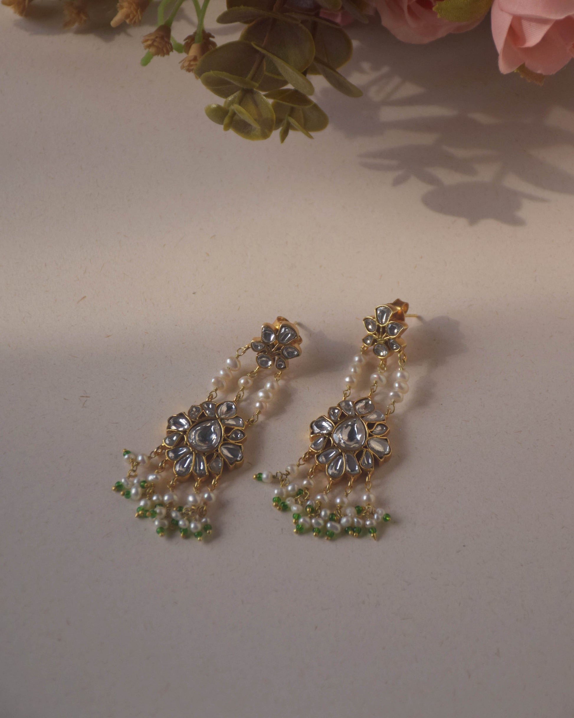 Jadau Pearl Drop Earrings crafted in 925 sterling silver featuring a flower-shaped top studded with jadau stones and an intricate jadau stone-studded motif suspended from three strands of pearls.