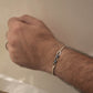 Hand wearing a silver Rakhi on a neutral background