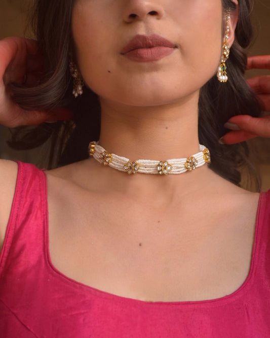 Premika Choker crafted in 925 silver, featuring floral motifs studded with white jadau stones and intricately intertwined guccha piroi design accented with delicate seed pearls.