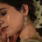 Avani Earrings crafted in 925 silver with gold polish, featuring delicate floral motifs adorned with jadau glass-filled stones, accented by drops of rice pearls and green aventurine beads