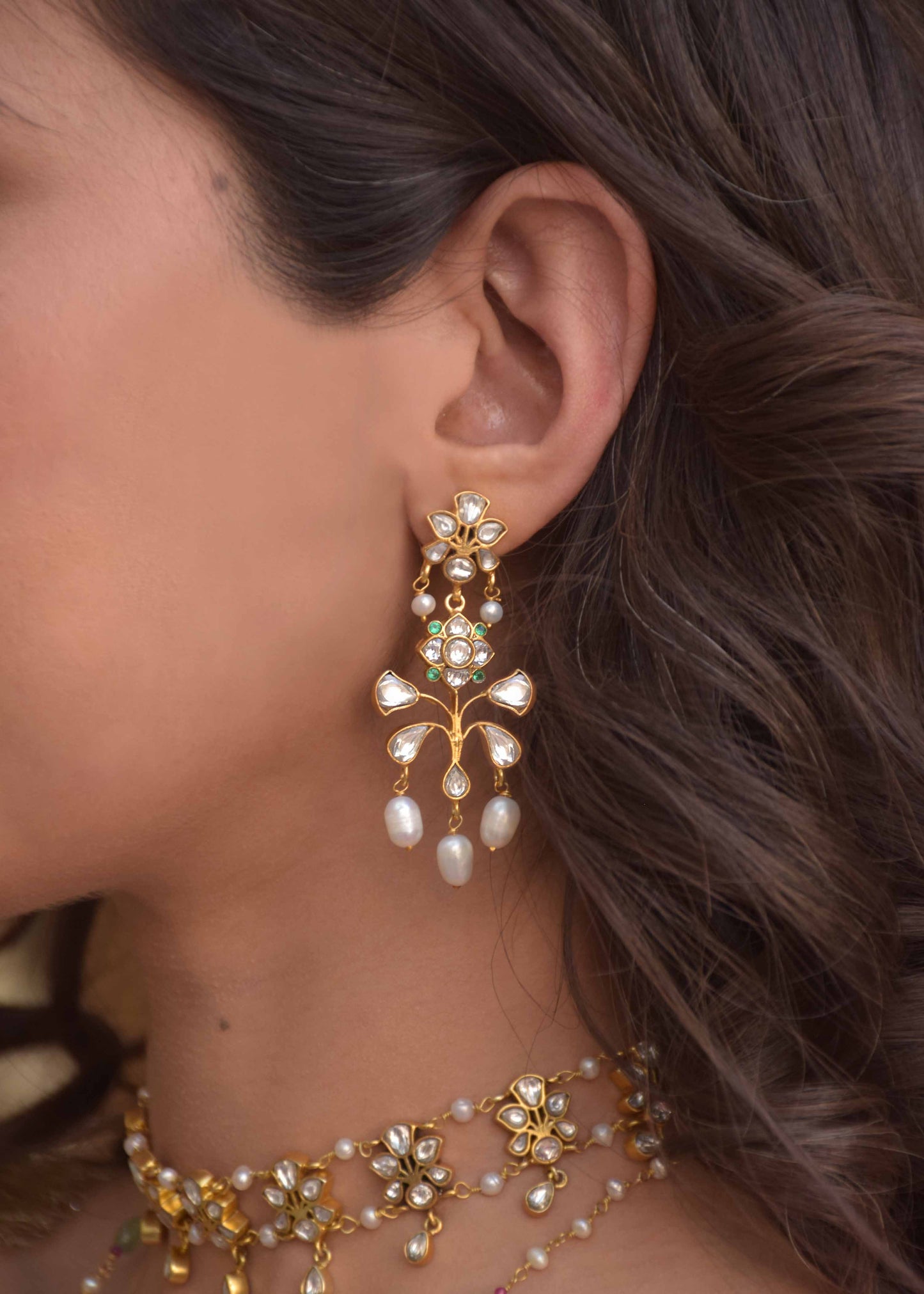 Matwaari Earrings crafted in 925 silver with gold polish, featuring a chandelier design with a stud embellished in white Jadau polkis and cascading rice pearls.