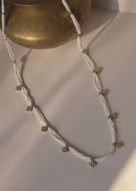 Nirjara Mala is a 30-inch necklace crafted with delicate flower-shaped Jadau units strung along elegant lines of seed pearls.