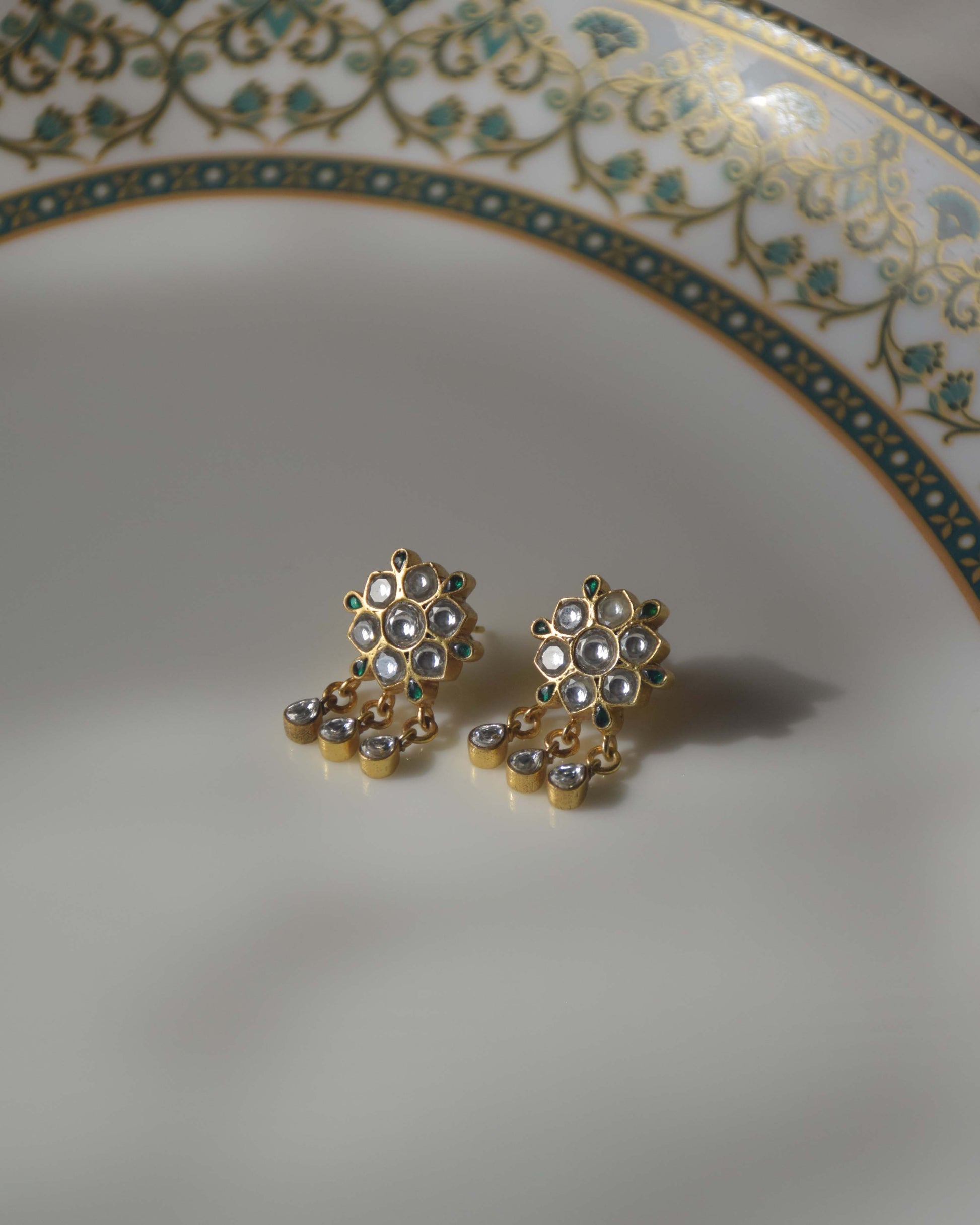  crafted in 925 silver, showcase an enchanting flower motif adorned with Jadau Stones and delicate hanging drops. 