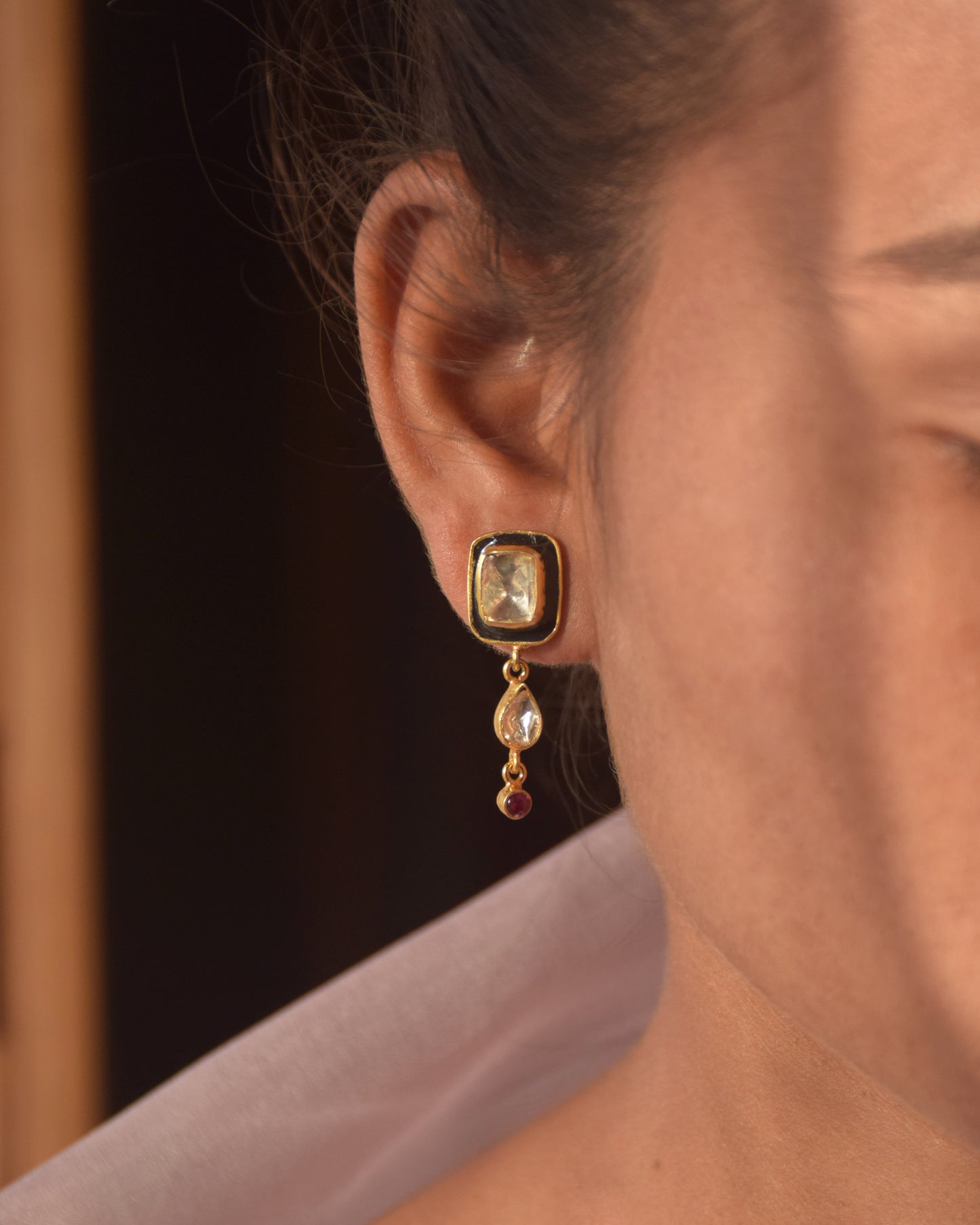 A striking Polki stone, adorned with deep black meena, with a dangling drop shape polki crafted in 92.5 Silver. 