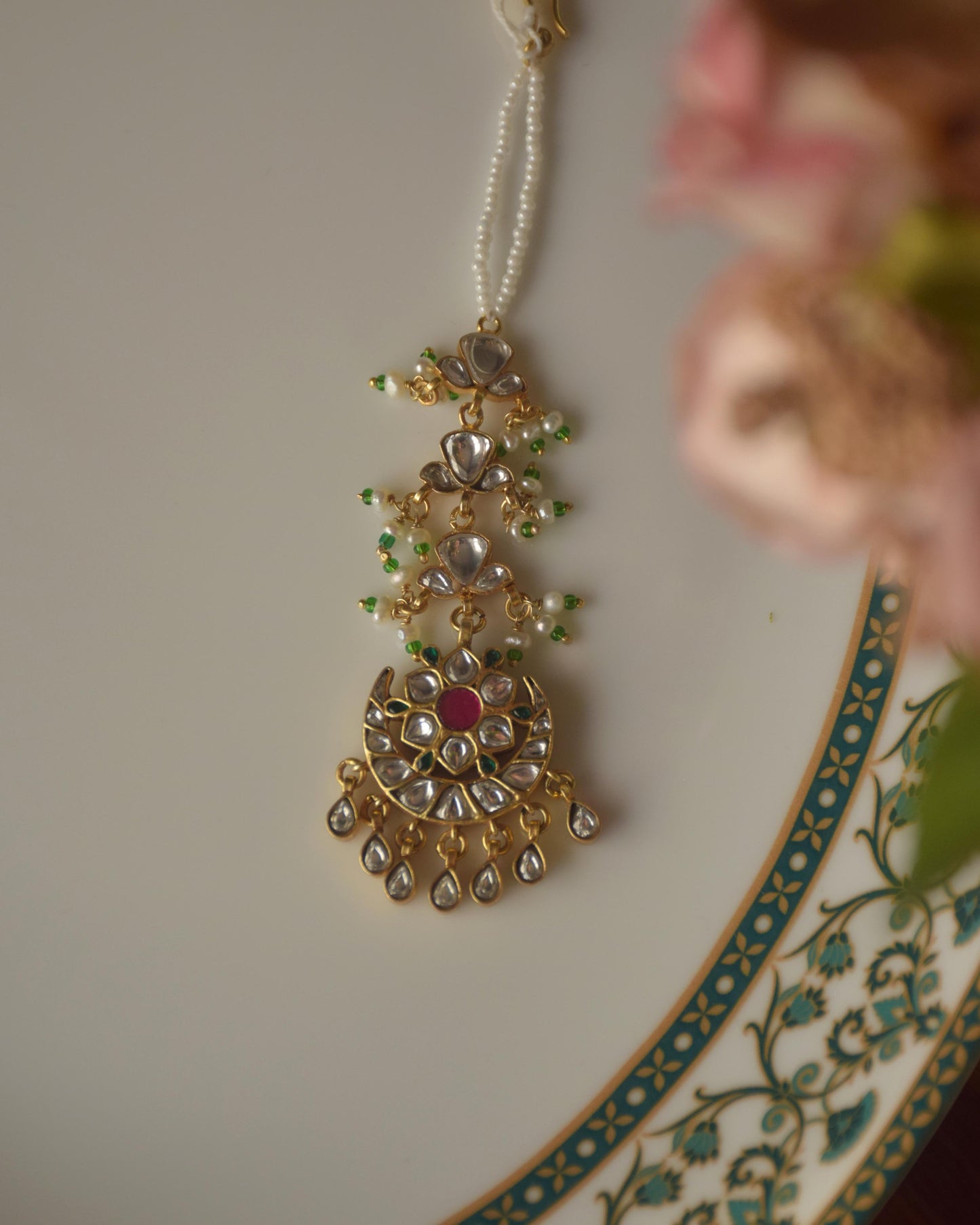 Chandphool Maangtika featuring a timeless Chand motif adorned with Jadau stones, connected to a line of Jadau-studded motifs and delicate trinket drops.