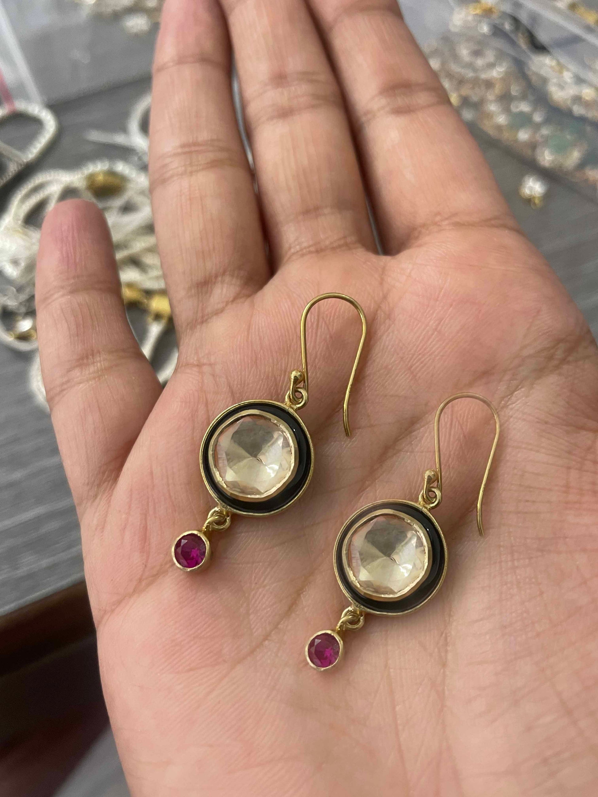 Gold-plated fish hoop earrings featuring a sparkling Polki stone accent and detailed black enamel work.