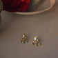 Maaeri earstuds in gold-plated 925 sterling silver featuring a handcrafted leaf motif with Jadau glass stones and three dangling freshwater pearls.