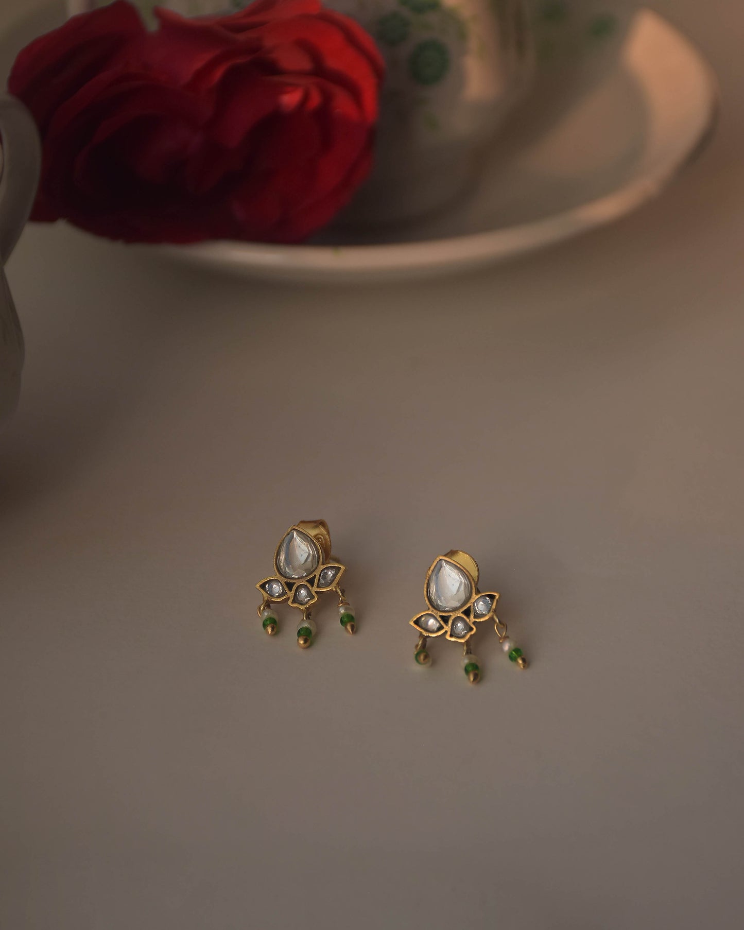 Maaeri earstuds in gold-plated 925 sterling silver featuring a handcrafted leaf motif with Jadau glass stones and three dangling freshwater pearls.