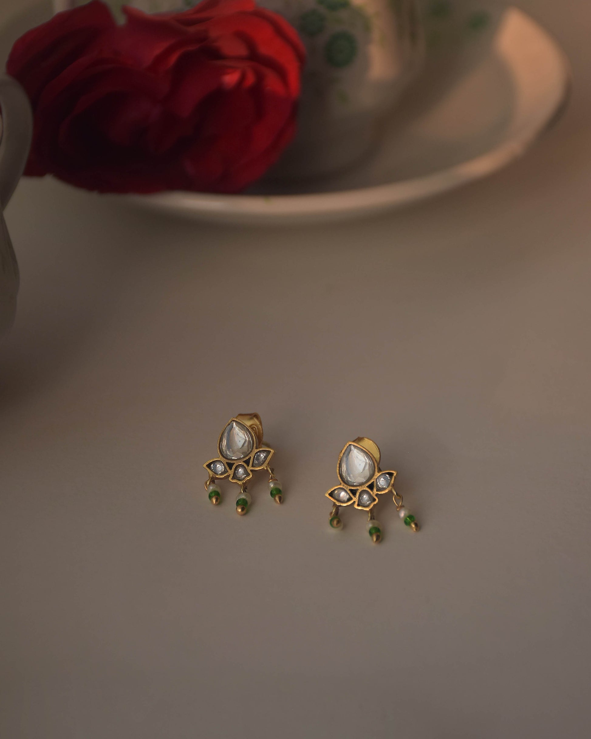 Maaeri earstuds in gold-plated 925 sterling silver featuring a handcrafted leaf motif with Jadau glass stones and three dangling freshwater pearls.