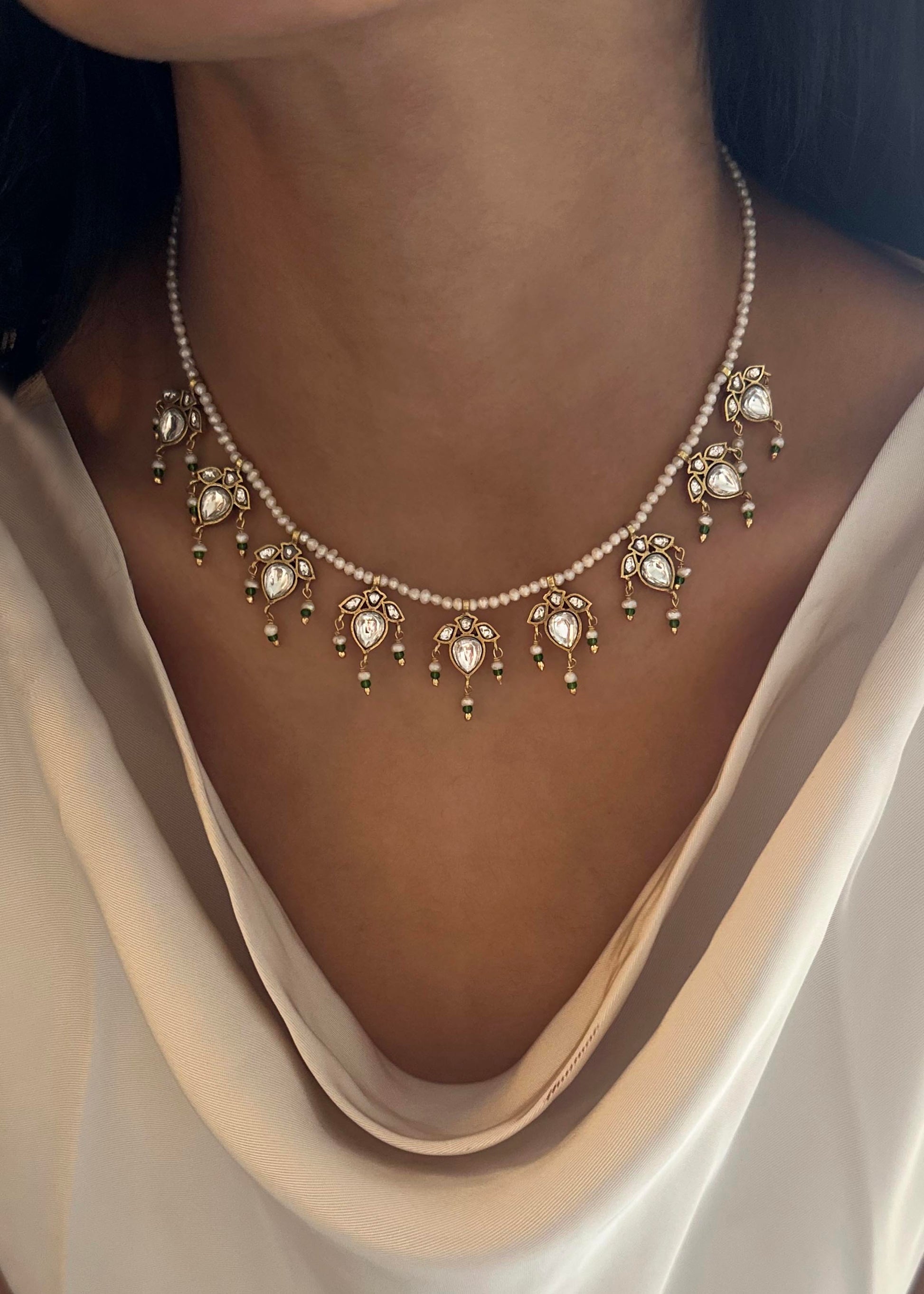 Maaeri necklace crafted in gold-plated 925 silver with a freshwater pearl string and a handcrafted leaf motif in Jadau glass stone work.