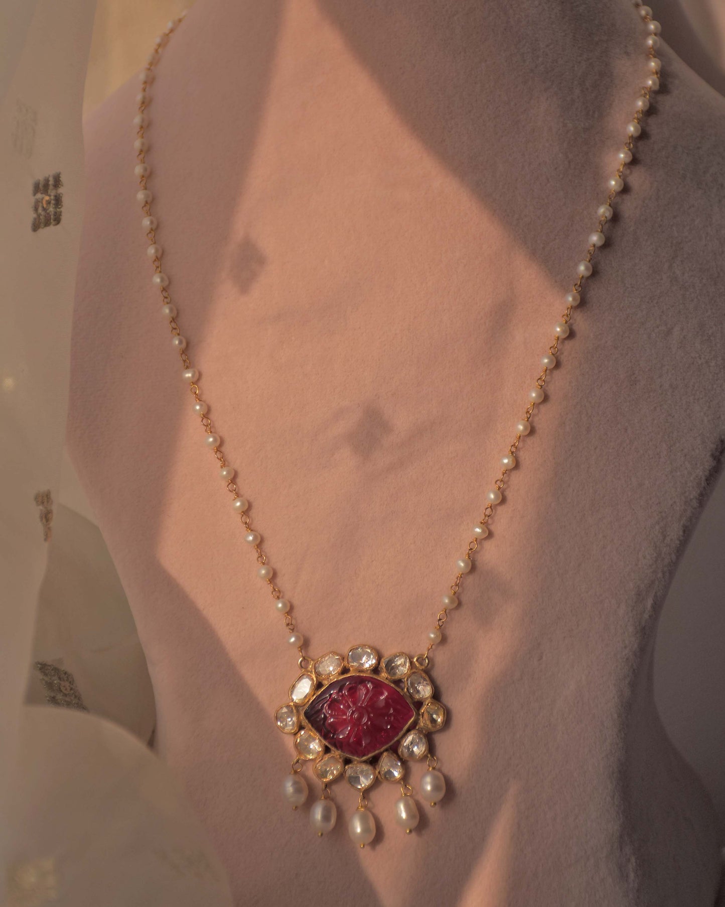 Handcrafted gold-plated silver pendant featuring a carved pink glass centerpiece, surrounded by Polki stones, paired with a freshwater pearl chain.