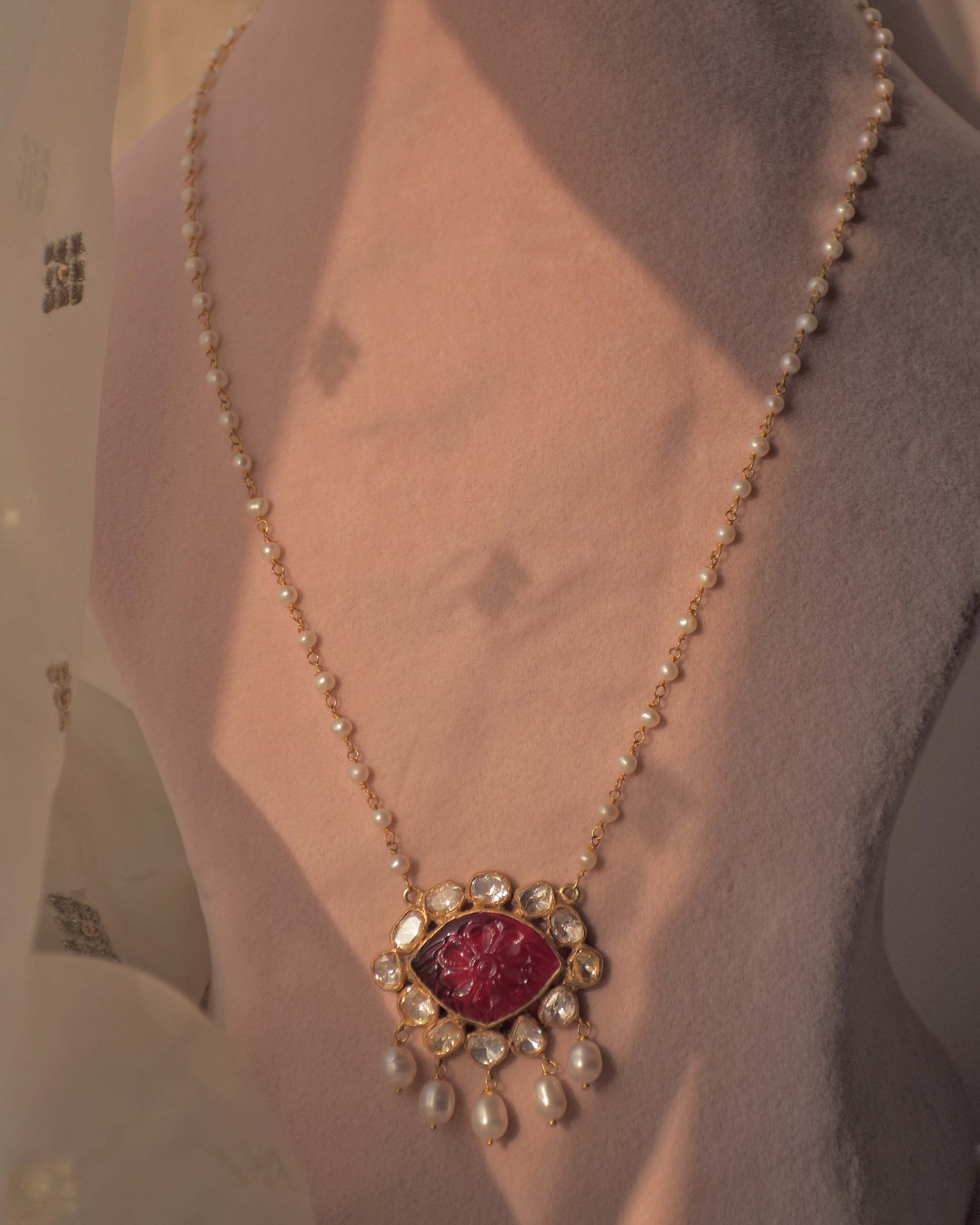 Handcrafted gold-plated silver pendant featuring a carved pink glass centerpiece, surrounded by Polki stones, paired with a freshwater pearl chain.