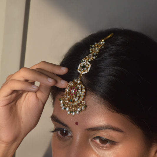 Hansa Maangtika handcrafted in 925 silver featuring floral motifs embellished with green, pink, and white Jadau stones, adorned with cascading rice pearls and aventurine beads.