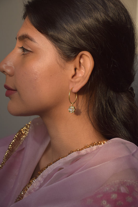 Elegant hoop earrings featuring a 4-petal Jadau stone-studded flower motif adorned with small green ad stones.