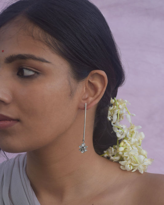  Minimalist long pipe earrings handcrafted in 92.5 sterling silver, featuring a floral motif embellished with white jadau stones. 