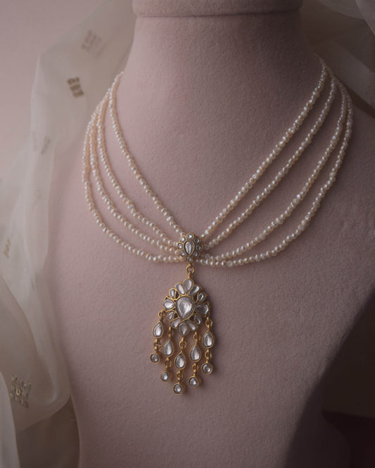 "Lehr Necklace handcrafted in 925 silver with intricate jadau work, featuring a bold central pendant and five strands of freshwater pearls.

