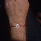 Red string bracelet with a lotus silver charm on a wrist