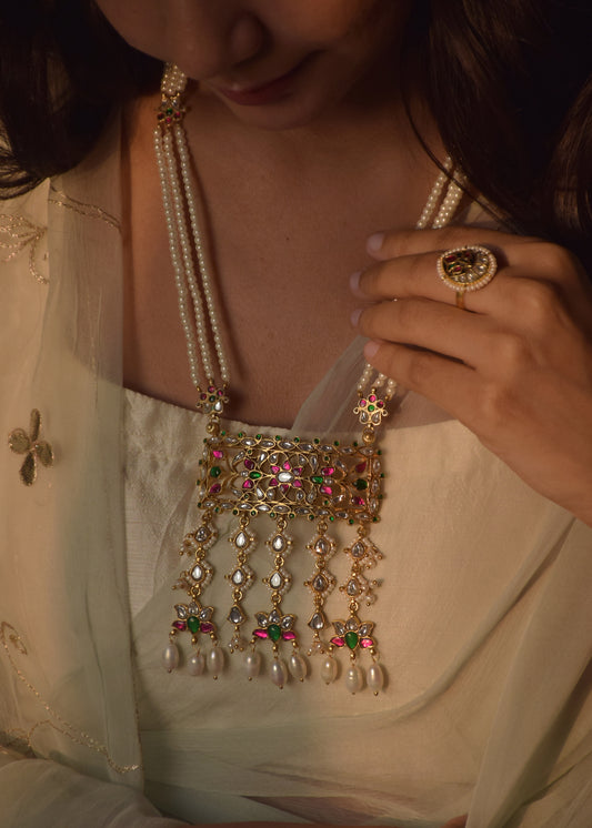 Manjari Necklace handcrafted in 925 silver featuring a rectangular design with intricate Jadau stonework, a lotus Jadau motif, seed pearl border, and elegant hanging pearl drops.