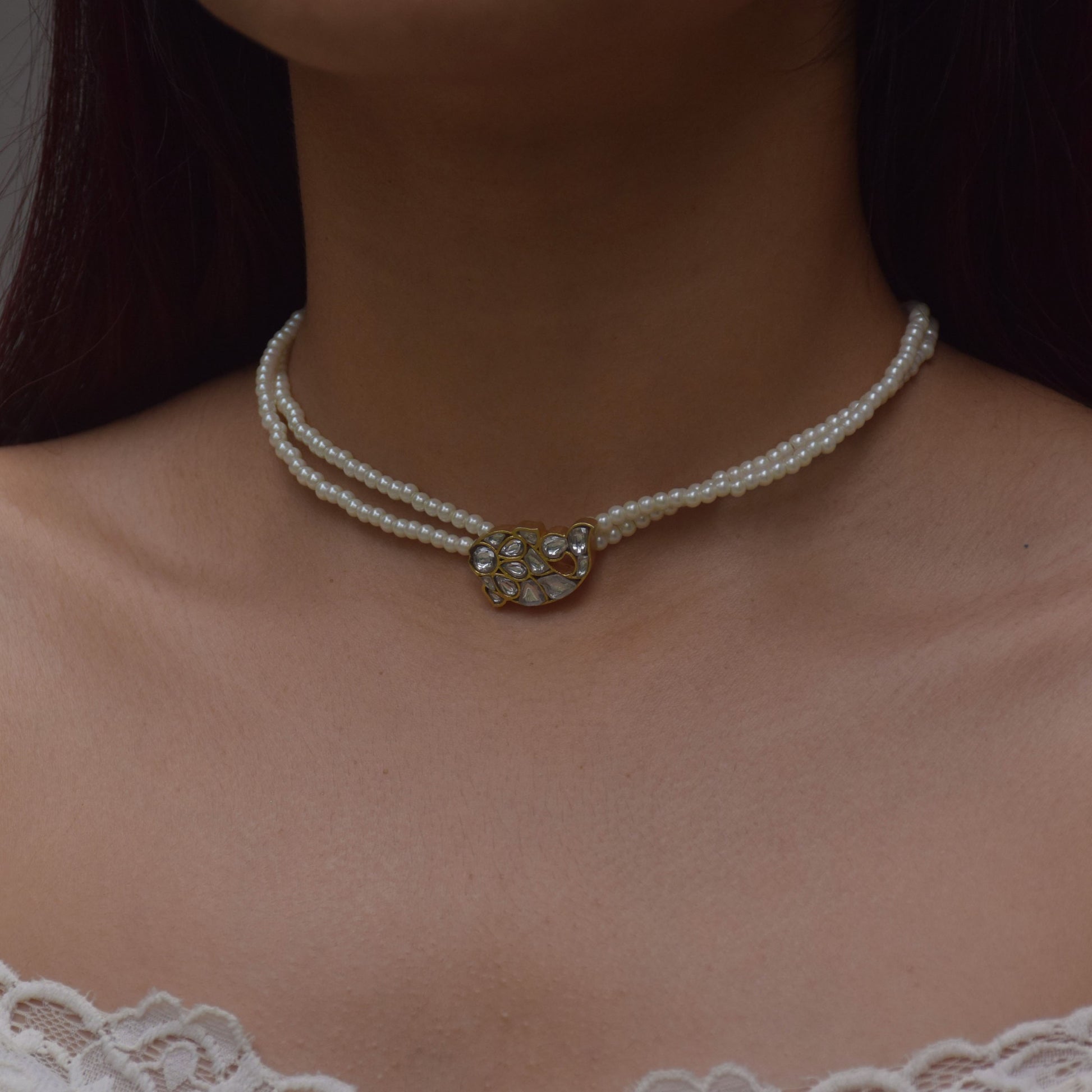 
"Nuvi Matsya Necklace in 925 silver featuring an intricately crafted fish motif adorned with white jadau stones, framed by delicate lines of lustrous shell pearls.