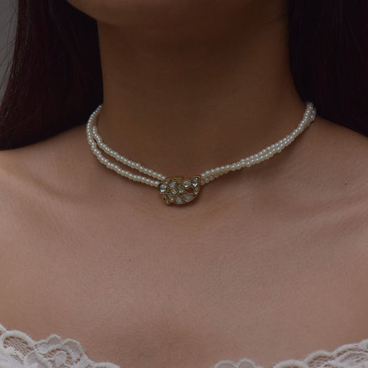 
"Nuvi Matsya Necklace in 925 silver featuring an intricately crafted fish motif adorned with white jadau stones, framed by delicate lines of lustrous shell pearls.