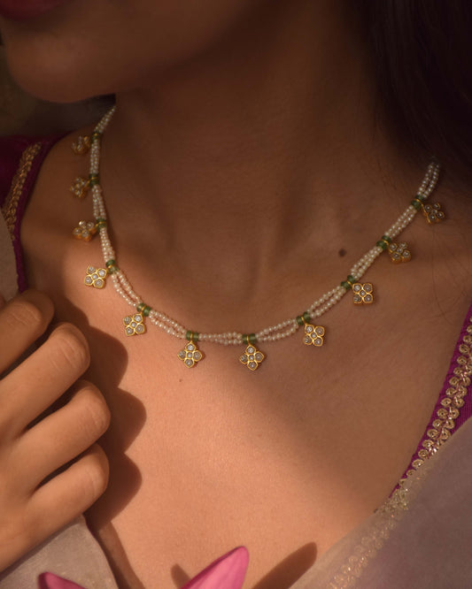 Raina Necklace handcrafted in 925 silver with four-petal floral motifs embellished with white jadau stones, strung on freshwater pearls with adjustable dori.