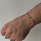 Hand with a red bracelet on a plain background