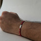 Red cootn thread Rakhi with 925 Silver unit on a wrist with a neutral background